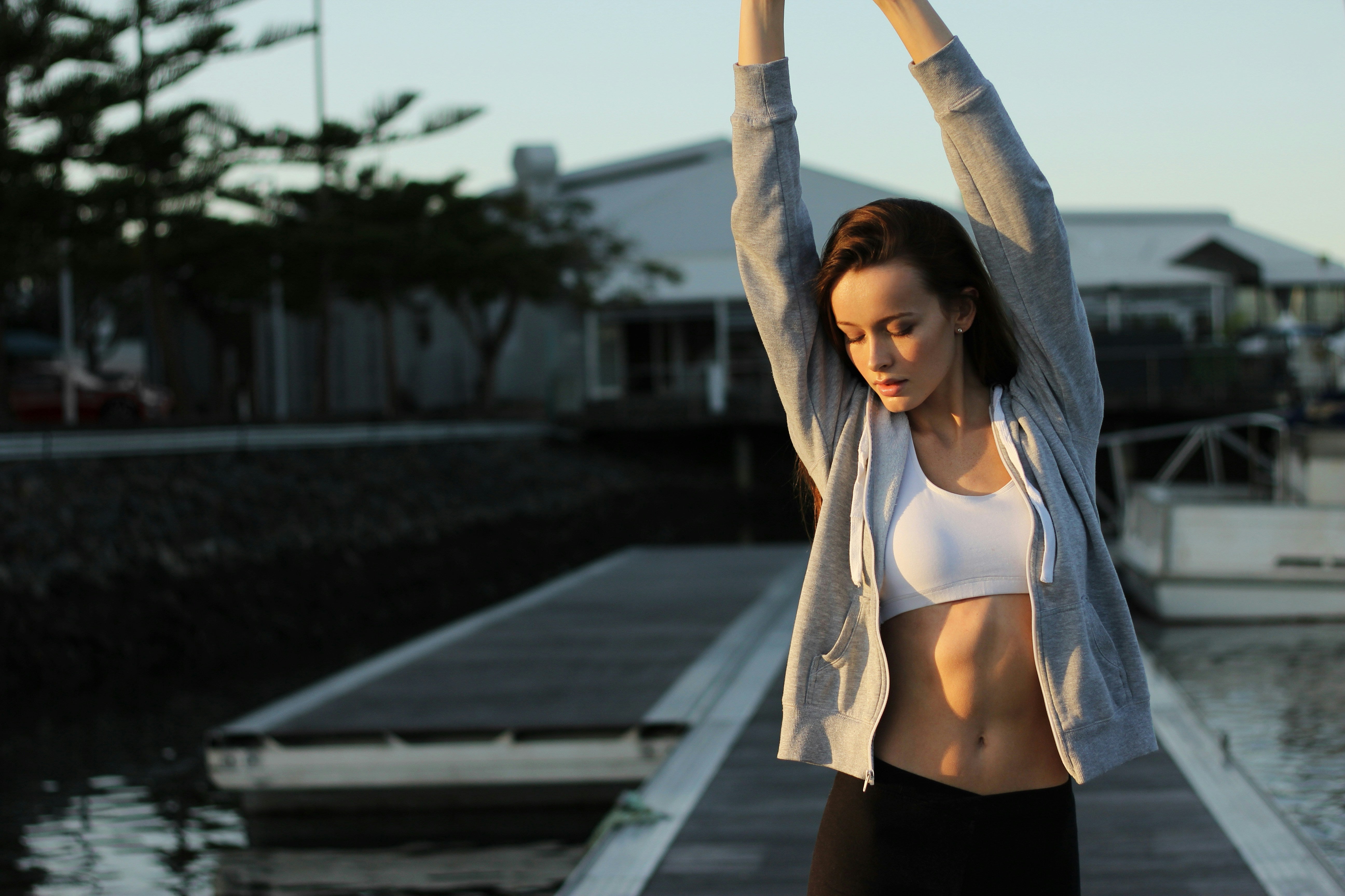 Woman stretching outdoors by a waterfront with houses in the background